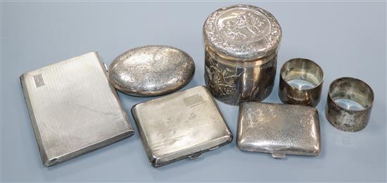 Three silver cigarette cases, a pair of silver napkin rings, a William Comyns embossed silver pot and an oval box